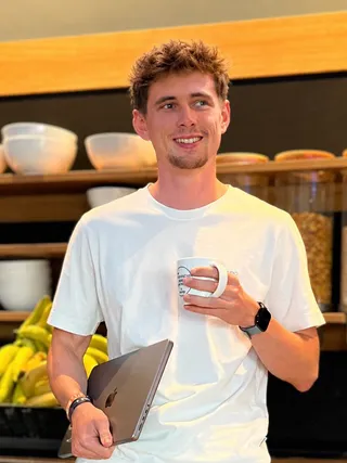 Frederik Mondel mit MacBook und Kaffeetasse – AuxCampus-Entwickler bei der Arbeit